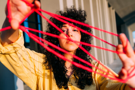 Woman playing cats cradle with thread