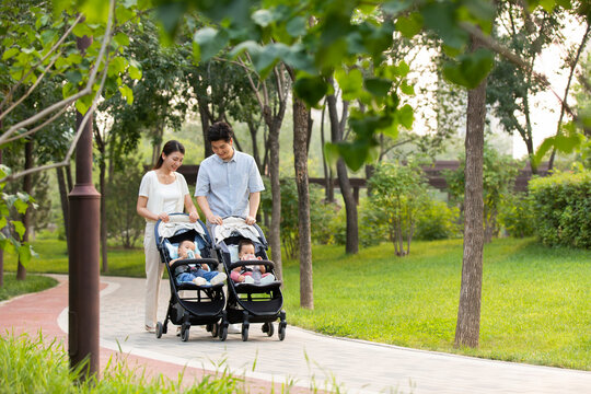 Young Chinese parents with twin babies in strollers