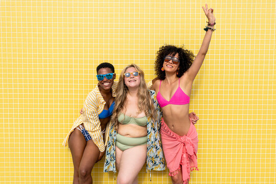 Happy multiracial friends in front of yellow wall