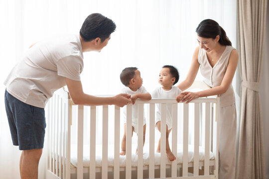 Young Chinese parents playing with twin babies at home