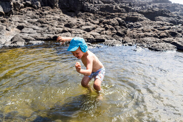 Fototapeta premium Small boy jumping to Charcones natural pools in.Lanzarote, Canary Islands, Spain