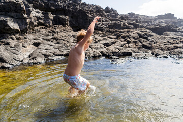 Small boy jumping to Charcones natural pools in.Lanzarote, Canary Islands, Spain