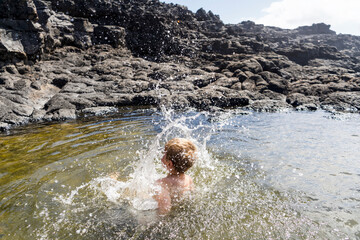 Small boy jumping to Charcones natural pools in.Lanzarote, Canary Islands, Spain
