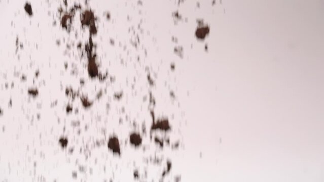 Crushed sandwich cookie dirt falling in mid air in slow motion on white backdrop