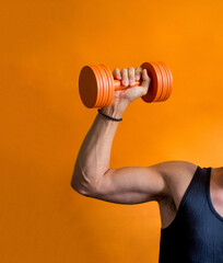 Fototapeta na wymiar photo of a sporty male torso with dumbbells in hand on an orange background