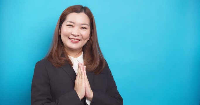 Beautiful Thai businesswoman in a black suit guests Sawadee with a smile on blue background
