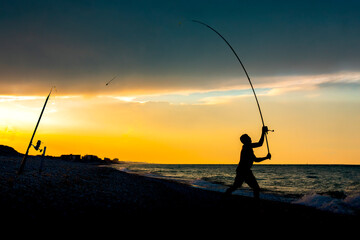Fisherman silhouette at sunset. Silhouette of a fisherman casting a rod on the coast at sunset.