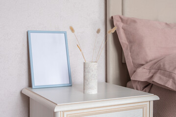 Template with photo frame on a wooden table. Bouquet of Lagurus. Sunlight from the window.