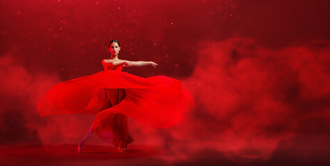 A young graceful ballerina, dressed in pointe shoes and a weightless red skirt, demonstrates her...