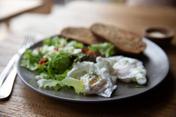 Fried Eggs on Wholegrain Toast and green salad for Breakfast. on wooden table