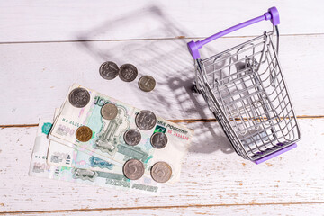 Still life: there is a grocery cart on the table and large Russian money with coins, the concept of...