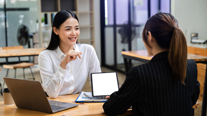 Asian people using and looking at mockup laptop computer on wooden table together on office desk with clipping path tablet.
