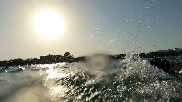 Young woman swimming backstroke at sunset sea. swimmer athlete finish her morning swimming workout at sunrise in open sea. Girl preparing for triathlon race in open water