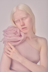 Portrait of beautiful elegant albino girl with elegant dress with big flower accessory posing at...