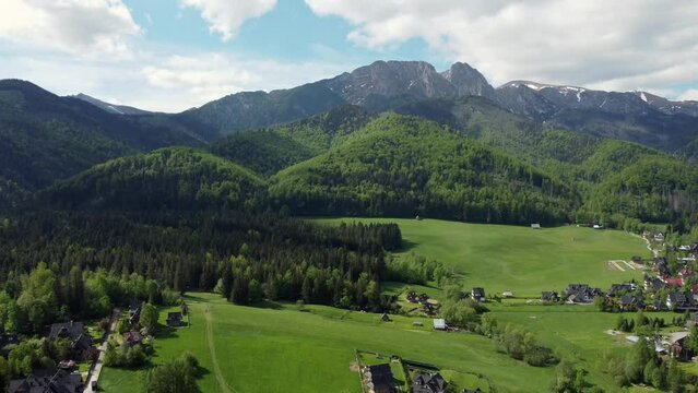 Landscape fly by of the legendary Giewont peak in the Polish Tatry Mountains, farmland, forests near Zakopane, Poland, a resort town with traditional Goral architecture. Cloudy summer day, epic hiking