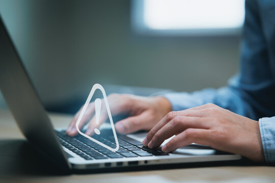 Businessman using computer laptop with triangle caution warning sing for notification error and maintenance concept.