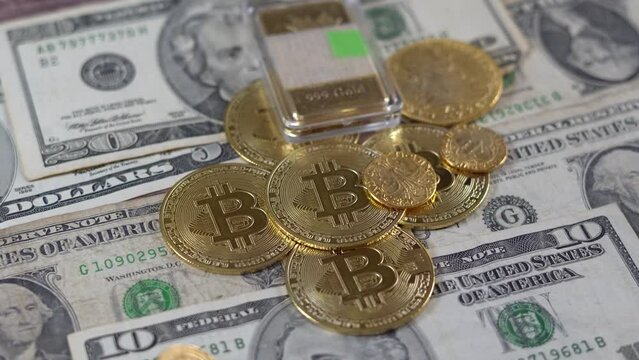 Monedas de Bitcoin y otras de oro y un lingote sobre billetes de dolares