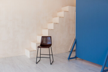 Brown chair over wall with stairs in the hipster interior modern room.