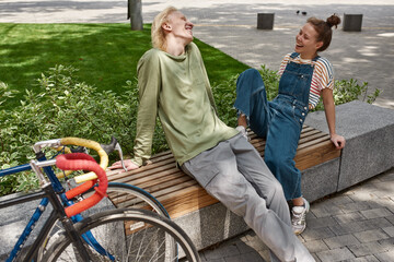 Laughing couple sit and rest on wooden bench