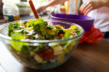 Transparent bowl of fresh green salad close up on a table kitchen background. Concept helpful and simple food