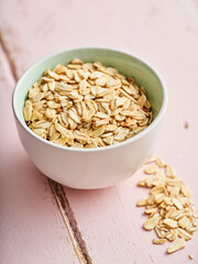 White bowl of oat on a pink background