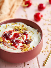 Bowl of yogurt served with cherry jam and peanuts