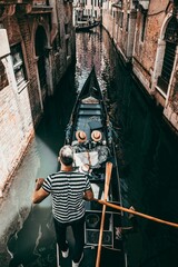 Vertical high-angle view of tourists taking gondola ride through the canal of Venice © Williamb/Wirestock Creators