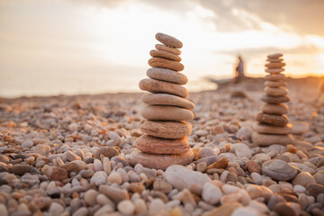 Fototapeta na wymiar Balanced harmony stones pyramid at beach coast. Summer sunset light. Zen meditation concept.