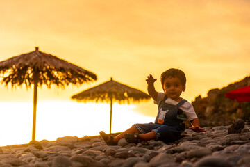 Sunset in Ponta do Sol, Madeira, a child playing with the stones on the beach in summer. Portugal