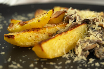 Close up of plate of baked potatoes and mushrooms in cream with herbs sprinkled with permesan cheese. Champignons. Food background.