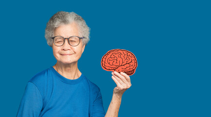 Portrait of a senior woman holding a brain symbol while standing on a blue background
