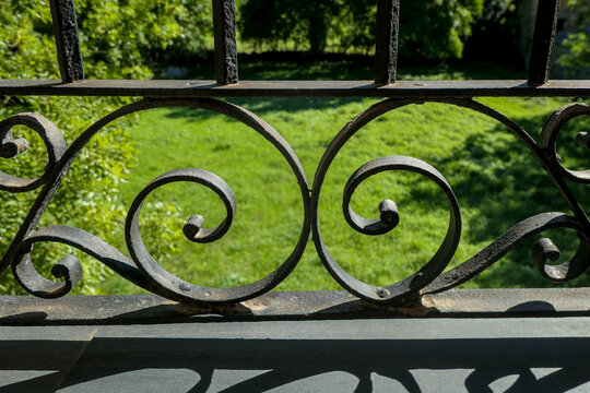 Black iron ornamental banister decorating a green grass garden  with the geometry in the spiral