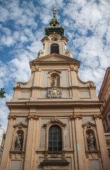 Fototapeta na wymiar Exterior view of the beautiful baroque Holy Cross church (Stiftskirche) which is located in the famous Mariahilfer Street in Vienna's 7th district, Neubau. Austria, Central Europe.
