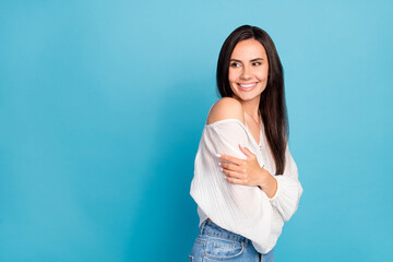 Photo of sweet dreamy young lady wear white top hugging herself looking empty space isolated blue color background