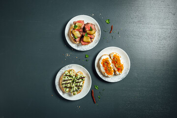 Fresh and helthy different kinds of colorful sandwiches on dark blue background, restaurant food, Party starter or appetizer - flat lay composition.