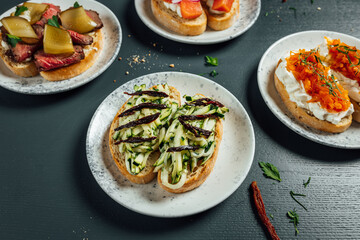 Fresh and helthy different kinds of colorful sandwiches on dark blue background, restaurant food, Party starter or appetizer - flat lay composition.
