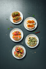 Fresh and helthy different kinds of colorful sandwiches on dark blue background, restaurant food, Party starter or appetizer - flat lay composition.