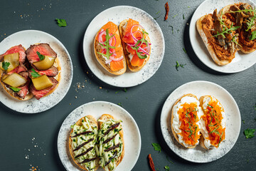 Fresh and helthy different kinds of colorful sandwiches on dark blue background, restaurant food, Party starter or appetizer - flat lay composition.
