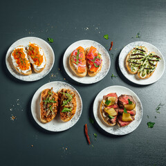 Fresh and helthy different kinds of colorful sandwiches on dark blue background, restaurant food, Party starter or appetizer - flat lay composition.