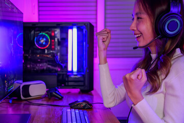 Winner gamer portrait, Young woman wearing headphones playing computer game, Female gamer winning...