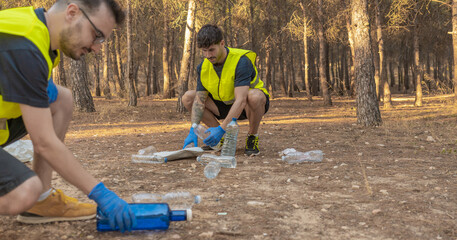 Dos jóvenes voluntarios, recogiendo basura en la montaña. Fotografía horizontal con espacio para texto. © Ezequiel Martínez