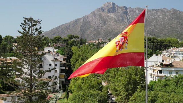 vista de la bonita bandera de España con la montaña del municipio de Marbella de fondo