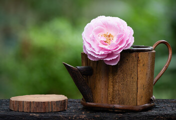 Damask rose flower in an old wooden coffee cup on nature background.
