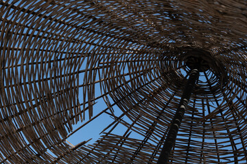 underside of a straw umbrella on the seaside coast, under shiny sun on the beach