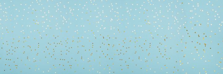 Star shaped shining golden confetti on light blue background. Sparkle sequins. Web banner with copy...
