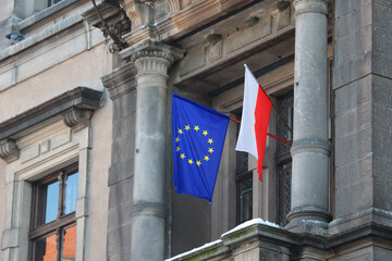 The flag of Poland and the European Union hangs on the building. - obrazy, fototapety, plakaty
