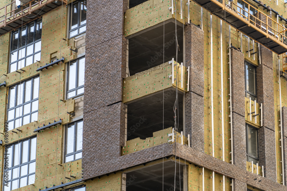 Poster monolithic concrete frame of apartment building under construction with partially attached facade cl
