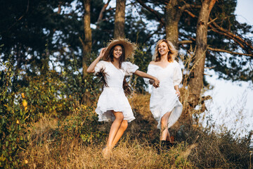 Naklejka na ściany i meble Mother with daughter in white dresses in forest