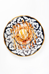 Round apple pie or tart topped with ice cream ball and sweet sauce