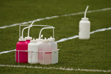 Water bottles for american football players on green grass at the edge of the playing field
